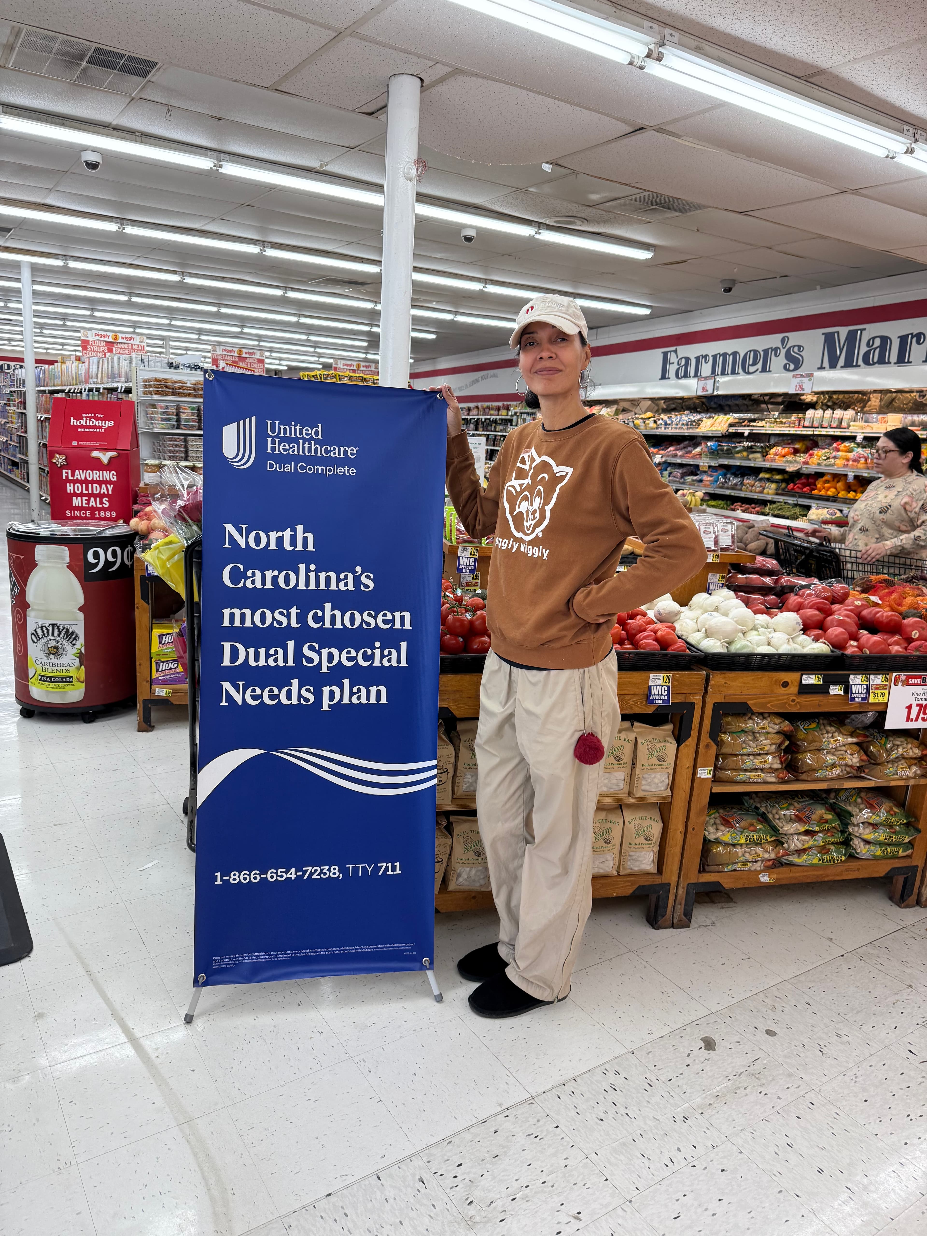 A shopper walking past a healthcare campaign banner inside a Piggly Wiggly grocery store